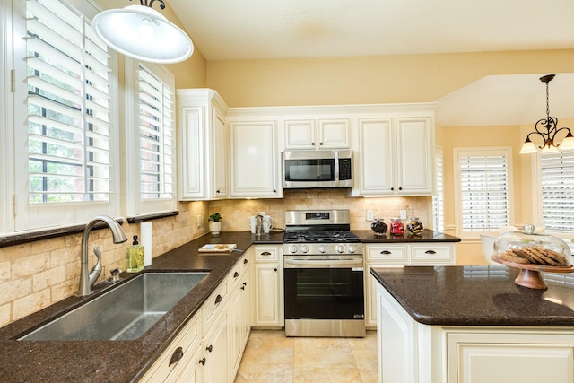 kitchen featuring a sink, appliances with stainless steel finishes, backsplash, and decorative light fixtures