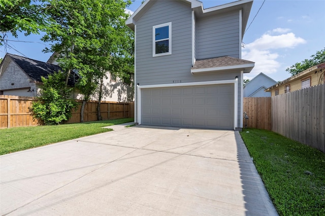 view of front facade with fence, roof with shingles, a front lawn, a garage, and driveway