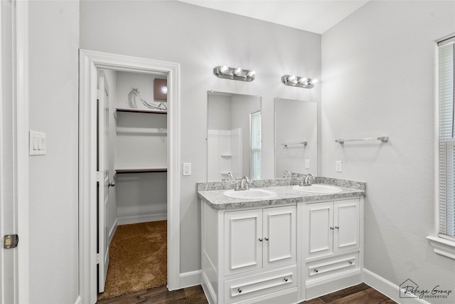 full bathroom featuring double vanity, a spacious closet, a sink, and wood finished floors