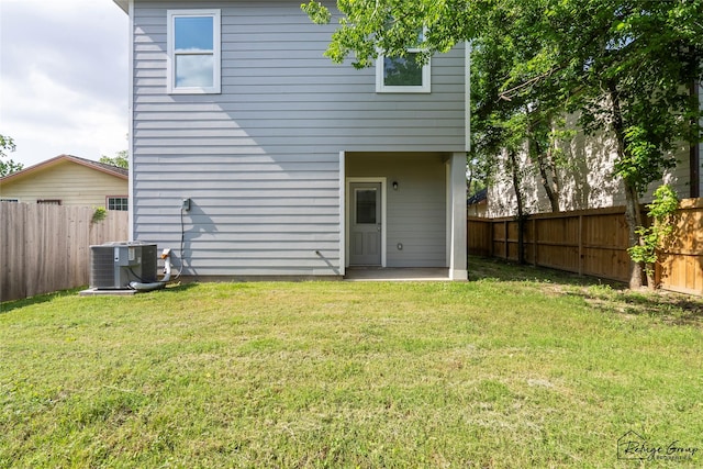back of house featuring a lawn, central AC unit, and a fenced backyard