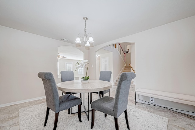 dining space with visible vents, arched walkways, stairway, baseboards, and ceiling fan with notable chandelier