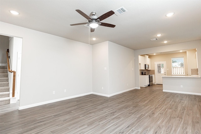 unfurnished living room with ceiling fan, light wood finished floors, stairs, recessed lighting, and visible vents