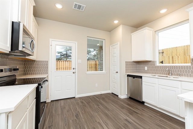 kitchen featuring visible vents, dark wood-style floors, white cabinetry, a sink, and appliances with stainless steel finishes