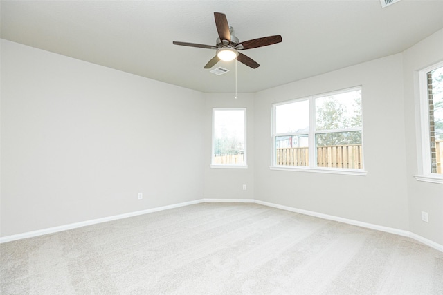unfurnished room featuring baseboards, ceiling fan, light colored carpet, and visible vents