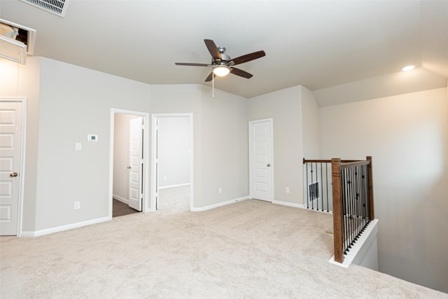 interior space featuring carpet, a ceiling fan, baseboards, lofted ceiling, and visible vents