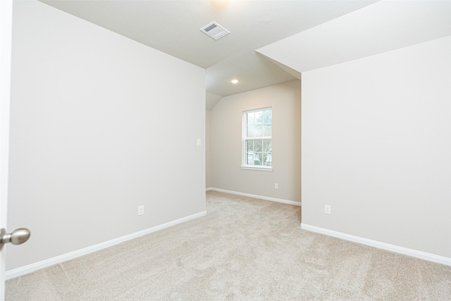 spare room featuring light colored carpet, visible vents, vaulted ceiling, baseboards, and recessed lighting