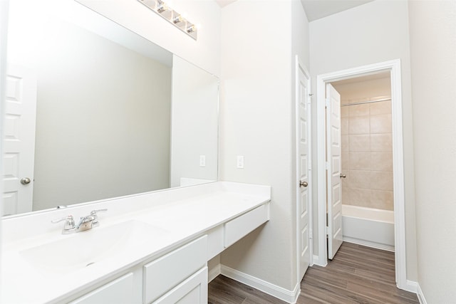 bathroom featuring baseboards, vanity, wood finished floors, and tub / shower combination