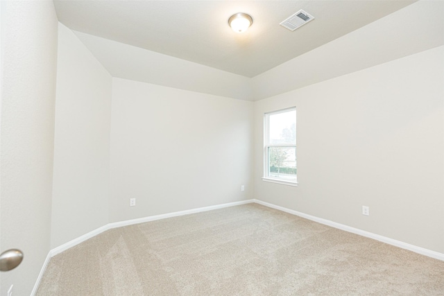 spare room featuring baseboards, light carpet, lofted ceiling, and visible vents