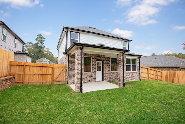 rear view of house with brick siding, a patio, a fenced backyard, and a lawn