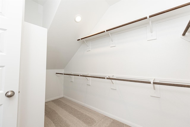 walk in closet featuring light colored carpet and vaulted ceiling