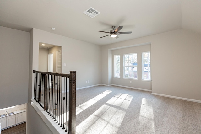 spare room with ceiling fan, visible vents, baseboards, and dark carpet