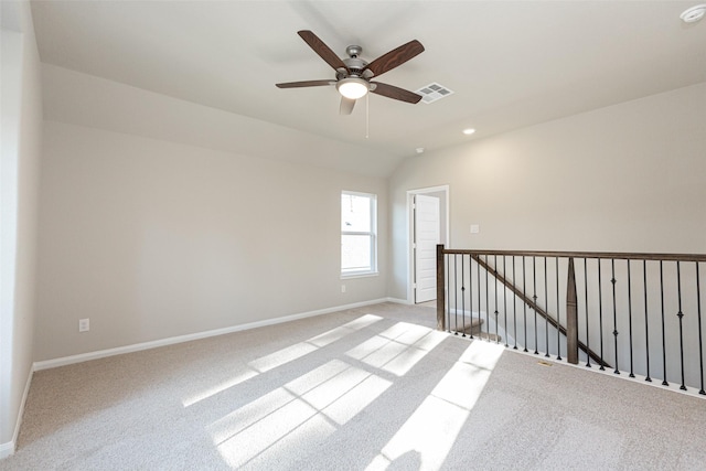 unfurnished room with carpet floors, a ceiling fan, baseboards, vaulted ceiling, and visible vents