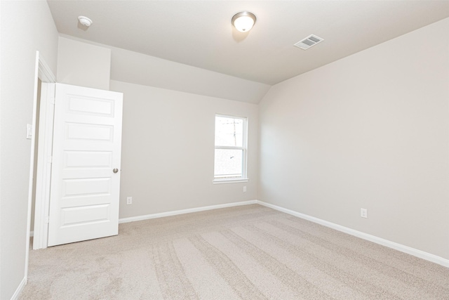 spare room featuring baseboards, visible vents, lofted ceiling, and carpet