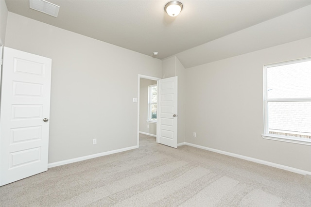 carpeted empty room featuring baseboards, visible vents, and lofted ceiling