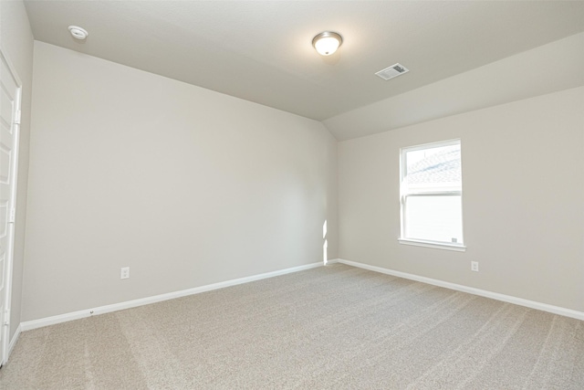 empty room featuring light colored carpet, baseboards, visible vents, and vaulted ceiling