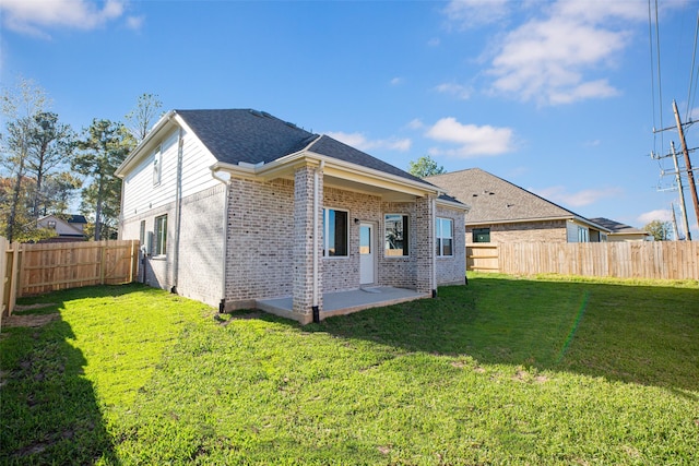 rear view of property with brick siding, a fenced backyard, a patio area, and a yard