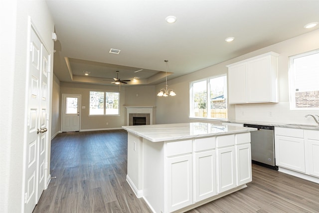 kitchen with a fireplace, dishwasher, a sink, ceiling fan with notable chandelier, and a tray ceiling