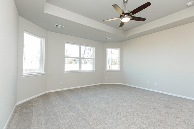 unfurnished room featuring a ceiling fan, visible vents, baseboards, a tray ceiling, and carpet flooring
