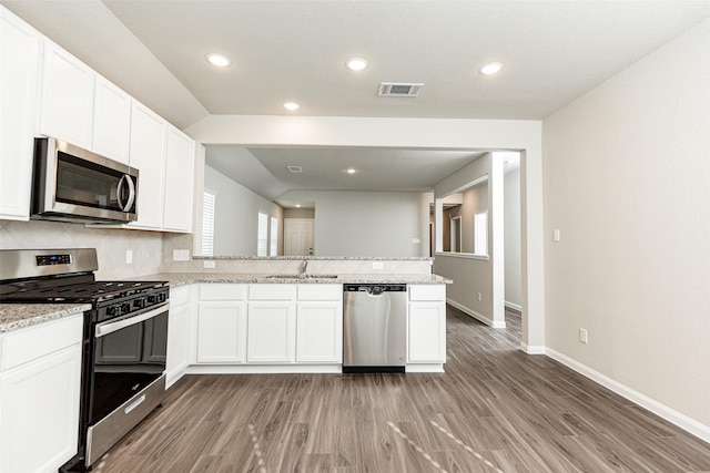 kitchen with visible vents, a peninsula, baseboards, light wood-style floors, and stainless steel appliances