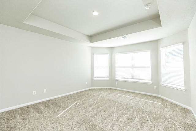 empty room featuring carpet floors, visible vents, baseboards, recessed lighting, and a tray ceiling
