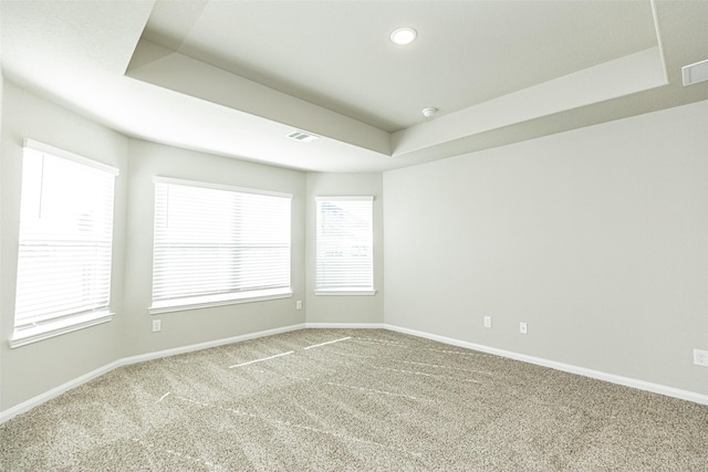 carpeted empty room featuring recessed lighting, a tray ceiling, visible vents, and baseboards
