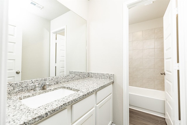 bathroom with visible vents,  shower combination, wood finished floors, and vanity