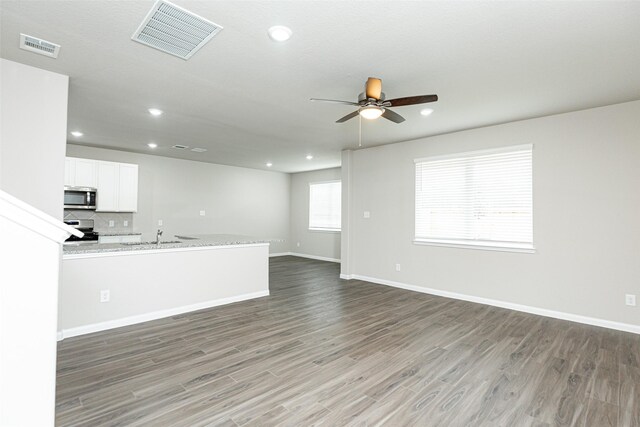 2897 Briggs Dr, Conroe, TX 77301 - unfurnished living room with baseboards, a ceiling fan, wood finished floors, and visible vents