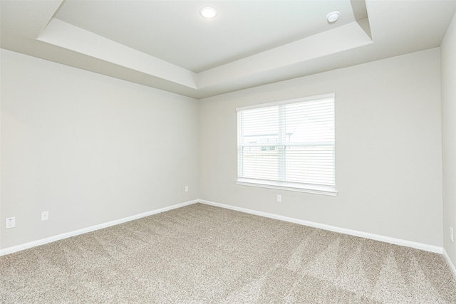 carpeted spare room featuring recessed lighting, baseboards, and a raised ceiling