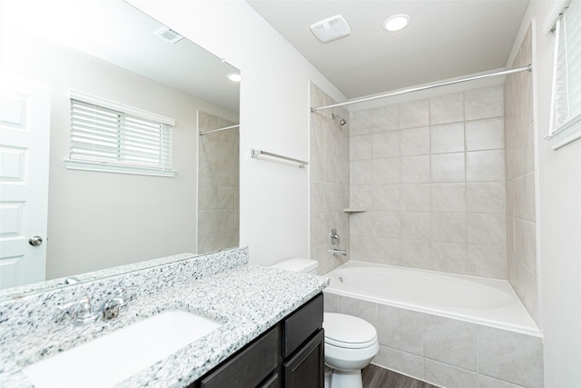 full bathroom with visible vents, vanity, tiled shower / bath, toilet, and recessed lighting