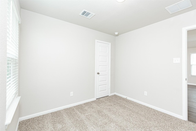 carpeted spare room featuring visible vents and baseboards