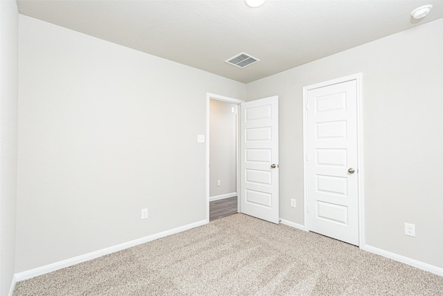 unfurnished bedroom with baseboards, carpet flooring, and visible vents