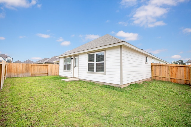 rear view of house featuring a lawn and a fenced backyard
