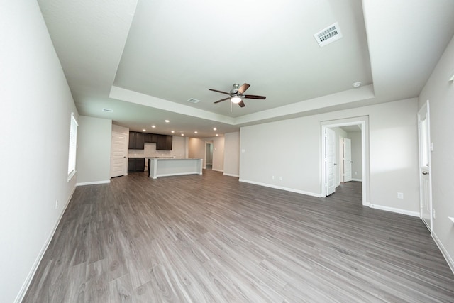 5107 Hector Gustavo Dr, Rosharon, TX 77583 - unfurnished living room featuring a tray ceiling, visible vents, baseboards, and a ceiling fan