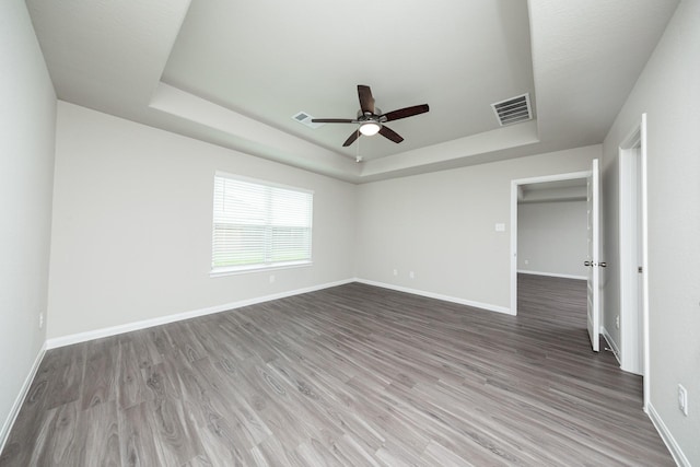 5107 Hector Gustavo Dr, Rosharon, TX 77583 - unfurnished bedroom with baseboards, a tray ceiling, visible vents, and wood finished floors