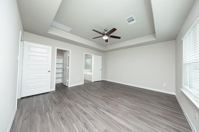 5107 Hector Gustavo Dr, Rosharon, TX 77583 - unfurnished bedroom featuring wood finished floors, a tray ceiling, a walk in closet, visible vents, and baseboards