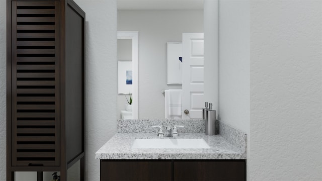 half bathroom featuring vanity and a textured wall