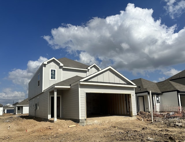 view of front of property with board and batten siding, an attached garage, and roof with shingles