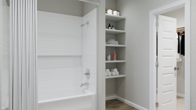 bathroom with a spacious closet, baseboards, wood finished floors, and shower / bath combination with curtain