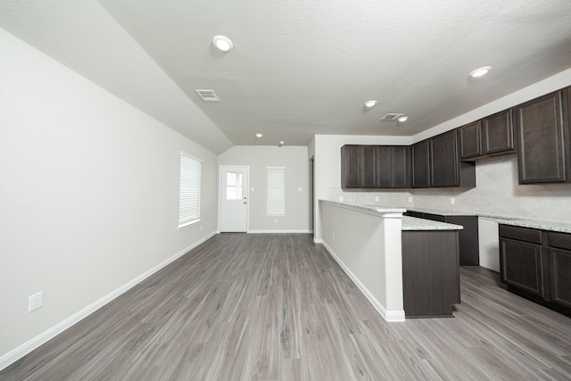 5114 Hector Gustavo Dr, Rosharon, TX 77583 - kitchen with light wood finished floors, dark brown cabinets, visible vents, baseboards, and vaulted ceiling