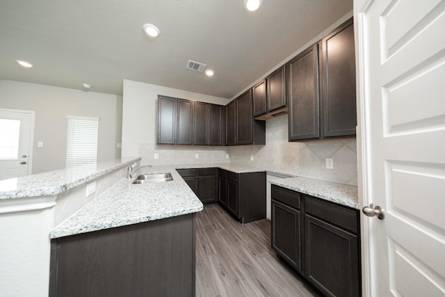 5114 Hector Gustavo Dr, Rosharon, TX 77583 - kitchen featuring light stone counters, visible vents, a sink, dark brown cabinetry, and backsplash