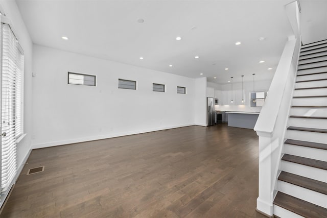 unfurnished living room featuring recessed lighting, visible vents, stairway, and dark wood-type flooring