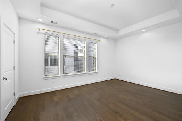spare room featuring recessed lighting, baseboards, dark wood-style floors, and a raised ceiling
