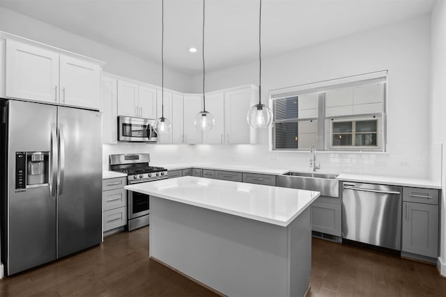 kitchen with a sink, appliances with stainless steel finishes, gray cabinetry, and dark wood finished floors