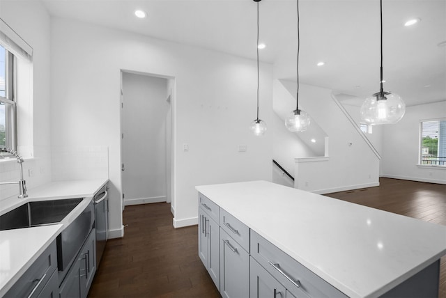 kitchen featuring stainless steel dishwasher, pendant lighting, recessed lighting, light countertops, and dark wood finished floors