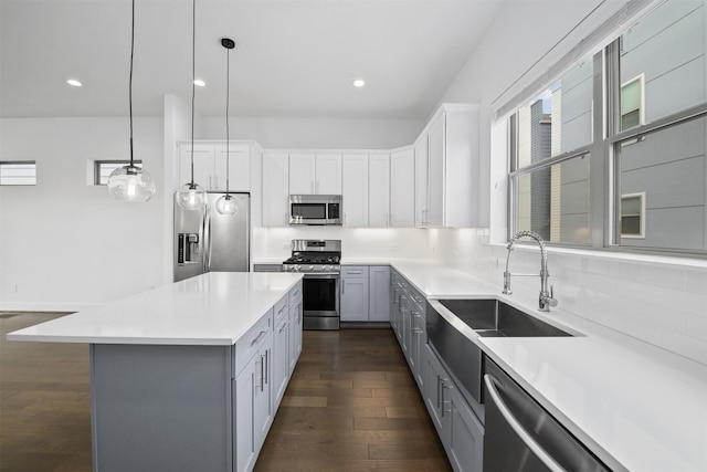 kitchen with dark wood-style floors, a center island, light countertops, a sink, and stainless steel appliances