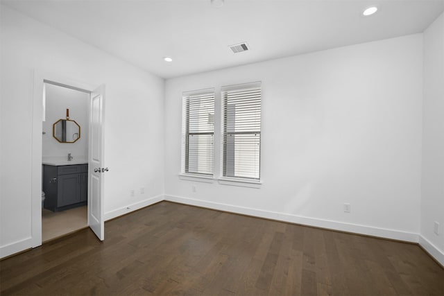 unfurnished bedroom featuring ensuite bath, recessed lighting, baseboards, dark wood-type flooring, and visible vents