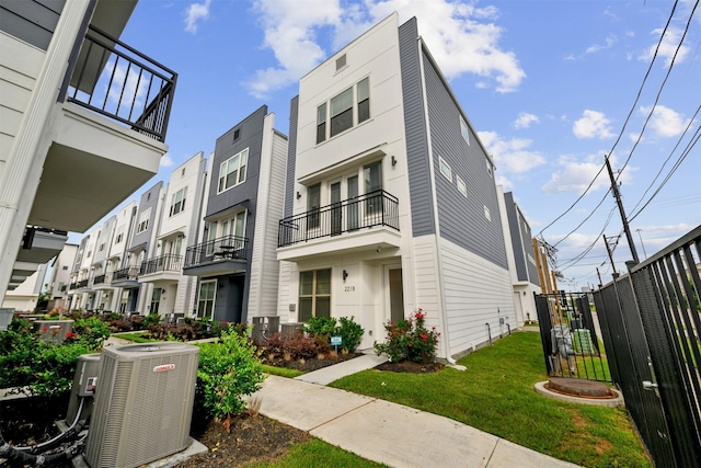 view of property with fence, central AC unit, and a balcony