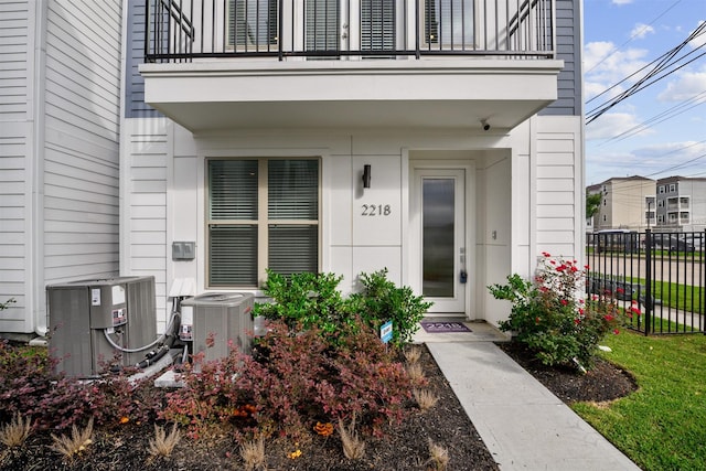 doorway to property featuring central AC unit, fence, and a balcony
