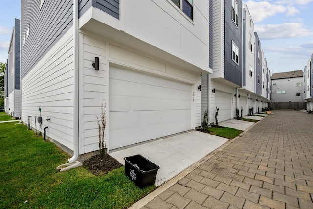 view of property exterior featuring concrete driveway, a yard, and a garage