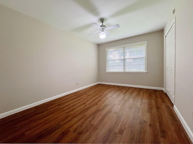 unfurnished bedroom featuring baseboards, ceiling fan, dark wood-style floors, and a closet